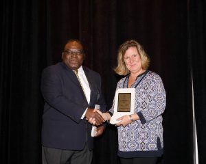 Laurie Webb accepts 2019 IMAA President's Award from IMAA Executive Director Calvin Lee.